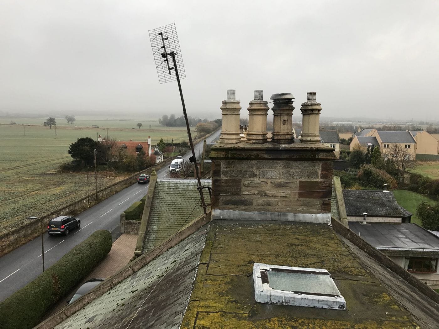 Storm-damaged TV aerial leaning off a stone chimney
